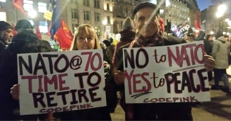 Medea Benjamin and fellow CODEPINK member holding anti-NATO placard