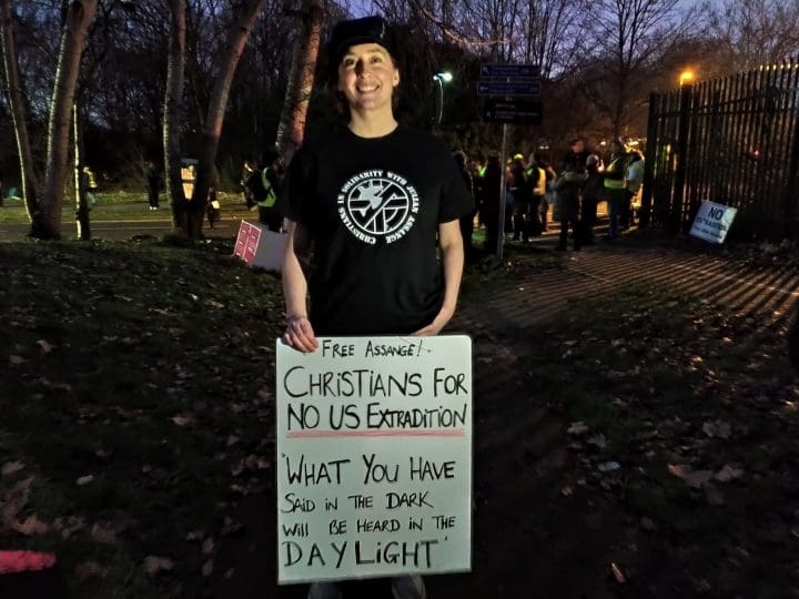 Jo Morrison stands with a banner quoting the new testimant Luke 12_3