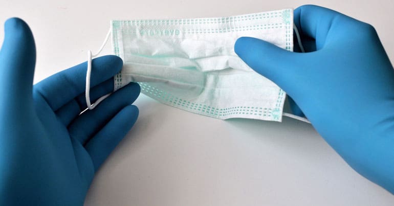 gloved hands holding a facemask