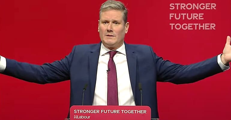 An image of Keir Starmer with his arms spread care Labour