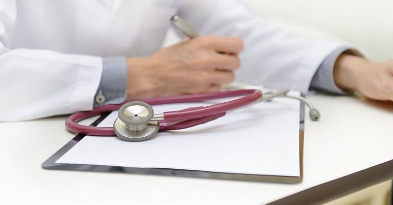 A doctor writing on a clipboard representing treatment for an eating disorder