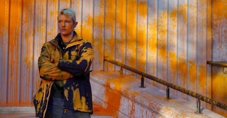 Just Stop Oil protester standing in front of a building with orange paint