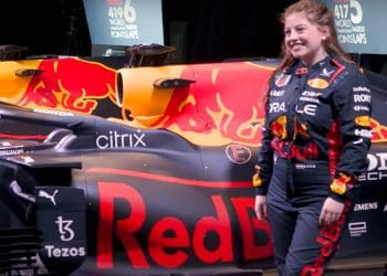 Female Red Bull Racing employee stands in front of race car.