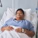 A woman with chronic illness lying in a hospital bed with ng feeding and an iv line