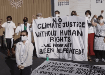 Climate protesters at COP27 with a banner that reads: No climate justice without human rights. We have not been defeated!