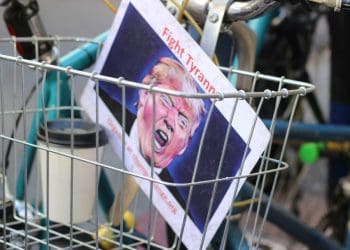 A poster at a protest features an image of Donald Trump with the headline "fight tyranny!"