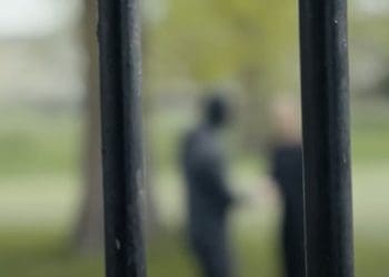 Prison bars, with someone in the distance blurred out behind Labour prison reform