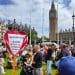 A group of chronically ill and disabled people protesting at parliament square with Big Ben in the background. It is a sunny day