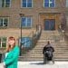 Labour housing policy a male wheelchair user at the bottom of a flight of outside steps leading up to a block of flats with Angela Rayner in a turquoise suit looking at the camera