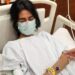 Severe ME/CFS patient Nevra in a hospital bed with her eyes closed, wearing a face-mask, and IV cannula attached to her wrist Pakistan