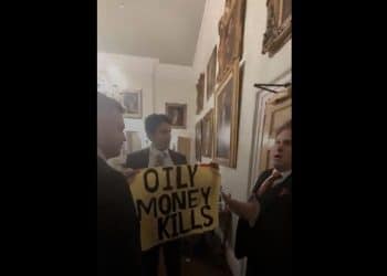 Activist holds a yellow banner reading: "Oily money kills" as two Republican supporters confront him during a state dinner celebrating Trump.