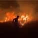 Silhouette of a firefighter standing amid a blazing wildfire climate crisis