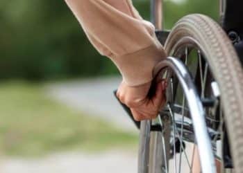 Close-up of a wheelchair-user's hand moving their wheelchair.