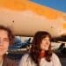Jennifer Kowalski and Cole Macdonald stand in front of a jet they've spray-painted orange.