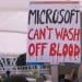 Protesters hold a placard reading "Microsoft can't wash off blood".