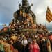 A huge crowd of people waving Catalonia's flag and climbing on a monument on La Diada.