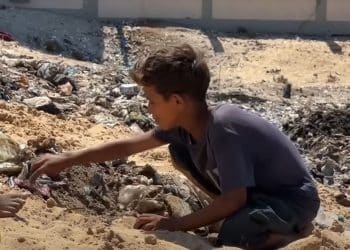A young Palestinian boy Israel has displaced in Gaza sits amid landfill.