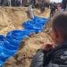 Palestinians bury a long line of bodies in a mass grave in Gaza. A child looks on. Gaza civilians killed