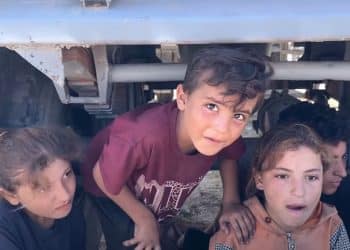 Palestinian children in Gaza climbing out from under the back of a vehicle.