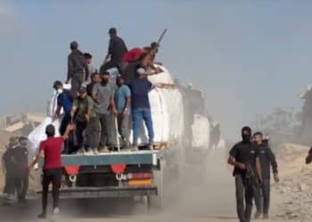Group of armed Palestinian men aboard the back of a vehicle, as masked men holding guns walk away from it to its rear Israel gangs Gaza