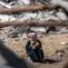Palestinian woman and her child sit amid the wreckage of buildings Israel has turned to rubble in Gaza.